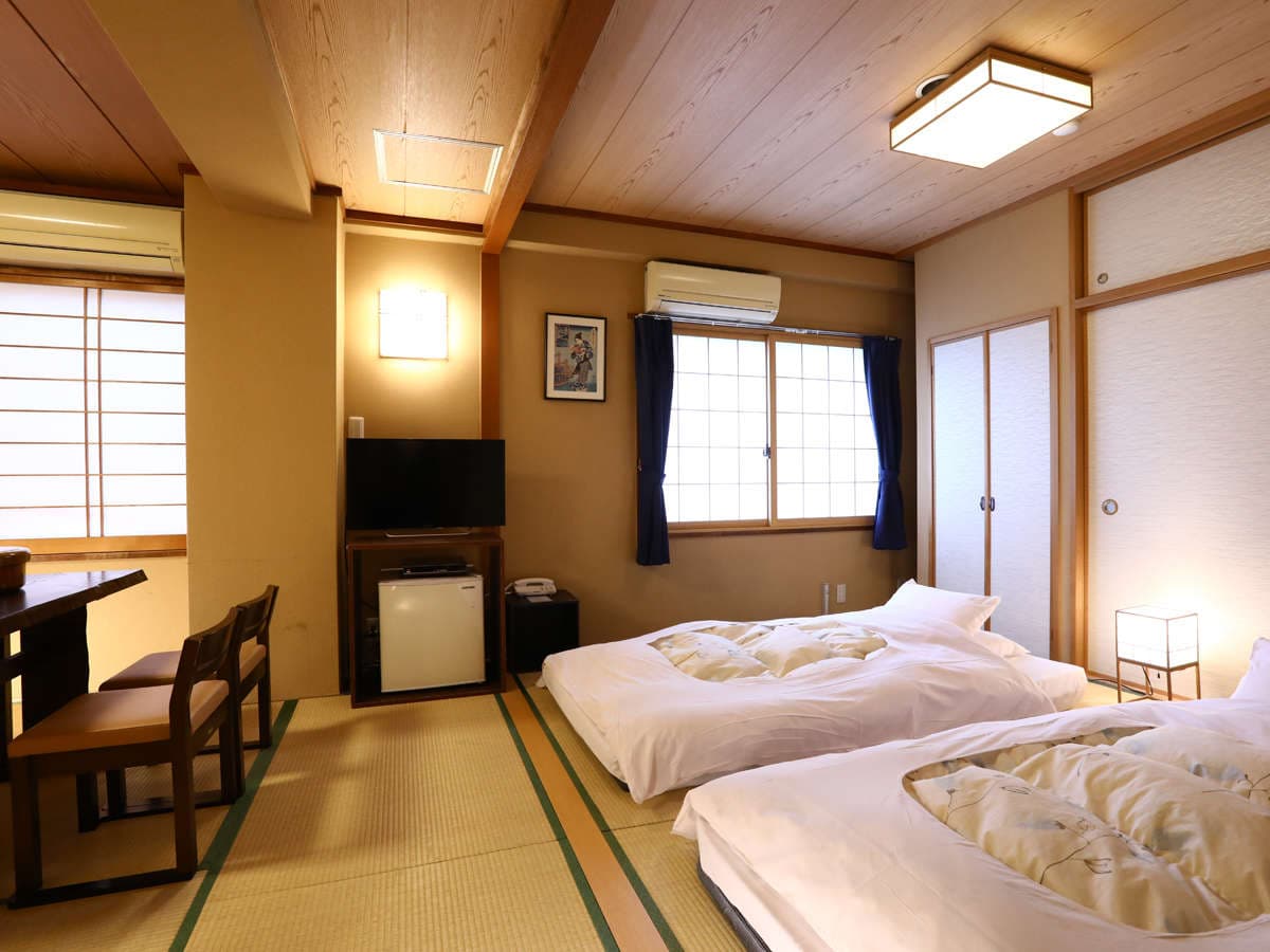 Spacious tatami guest room at Ryokan Kamogawa Asakusa with twin futons laid out, low table and shoji windows