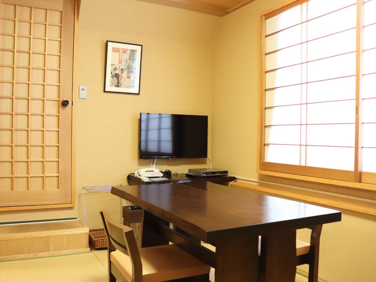 Compact tatami guest room at Ryokan Kamogawa Asakusa with wooden desk, flat-screen TV and framed ukiyo-e print