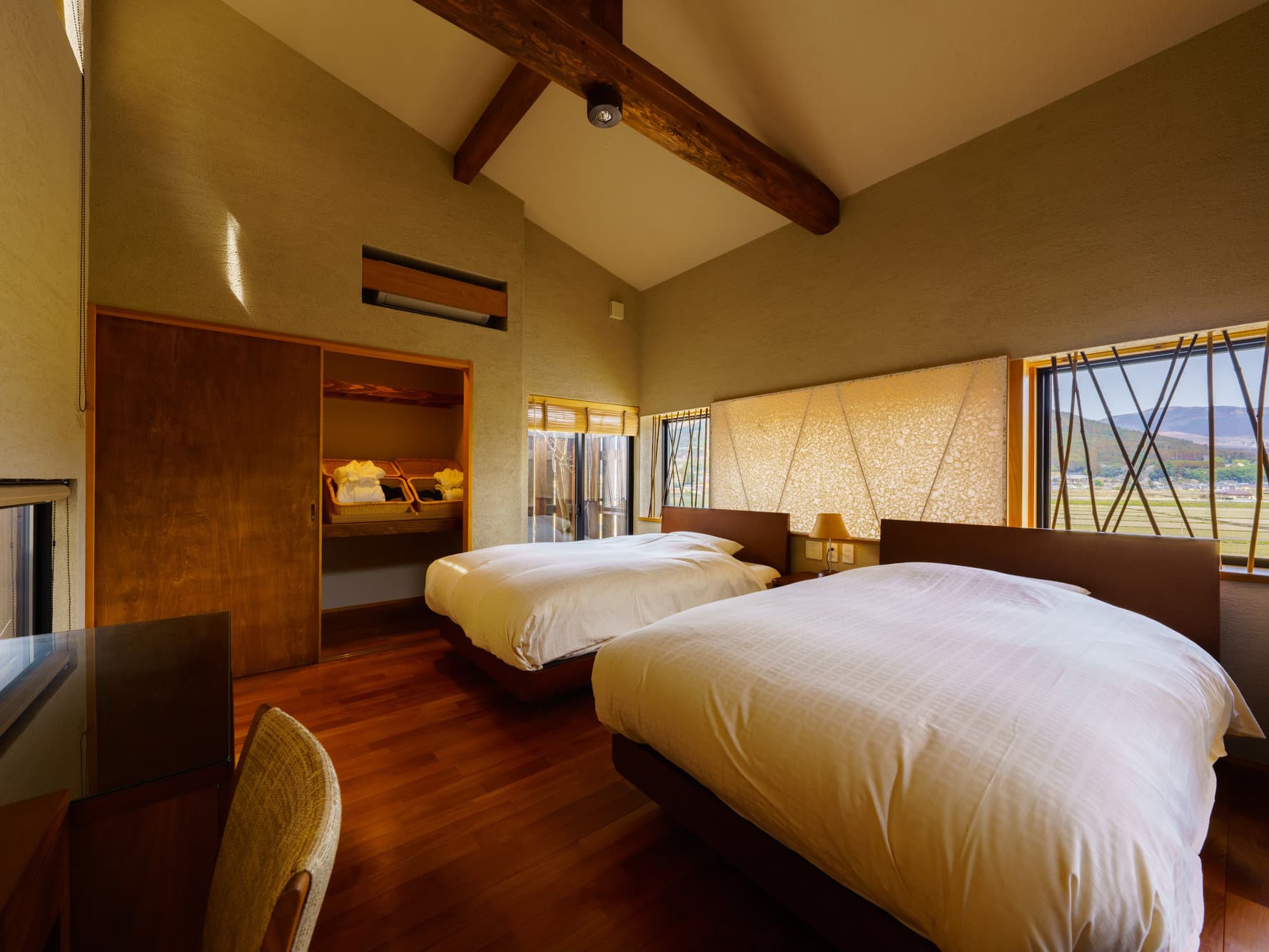 Twin bedroom with vaulted ceiling and exposed beam at Tosyoan, Yufuin, with mountain views from the windows