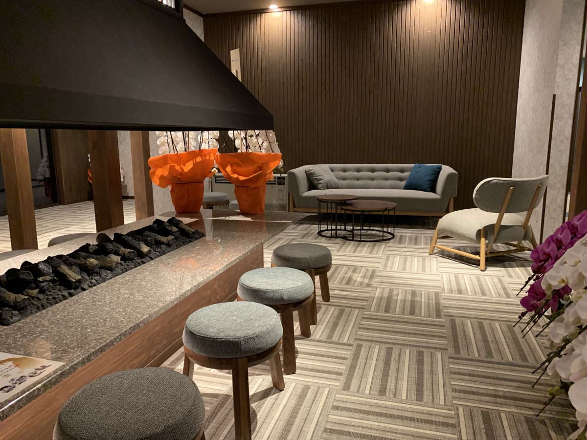 Lobby lounge with a long fireplace, cushioned stools, sofa and orchid arrangements