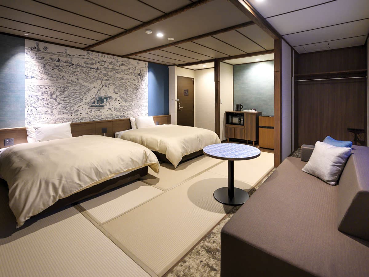Spacious tatami room with twin beds and an old Kusatsu Onsen map mural on the wall