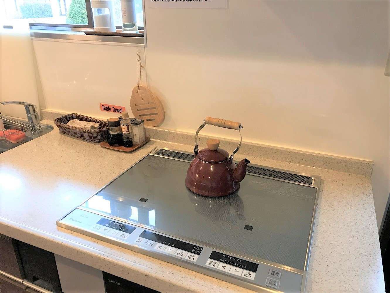 Guest self-catering kitchen with induction cooktop, kettle and condiments by a window