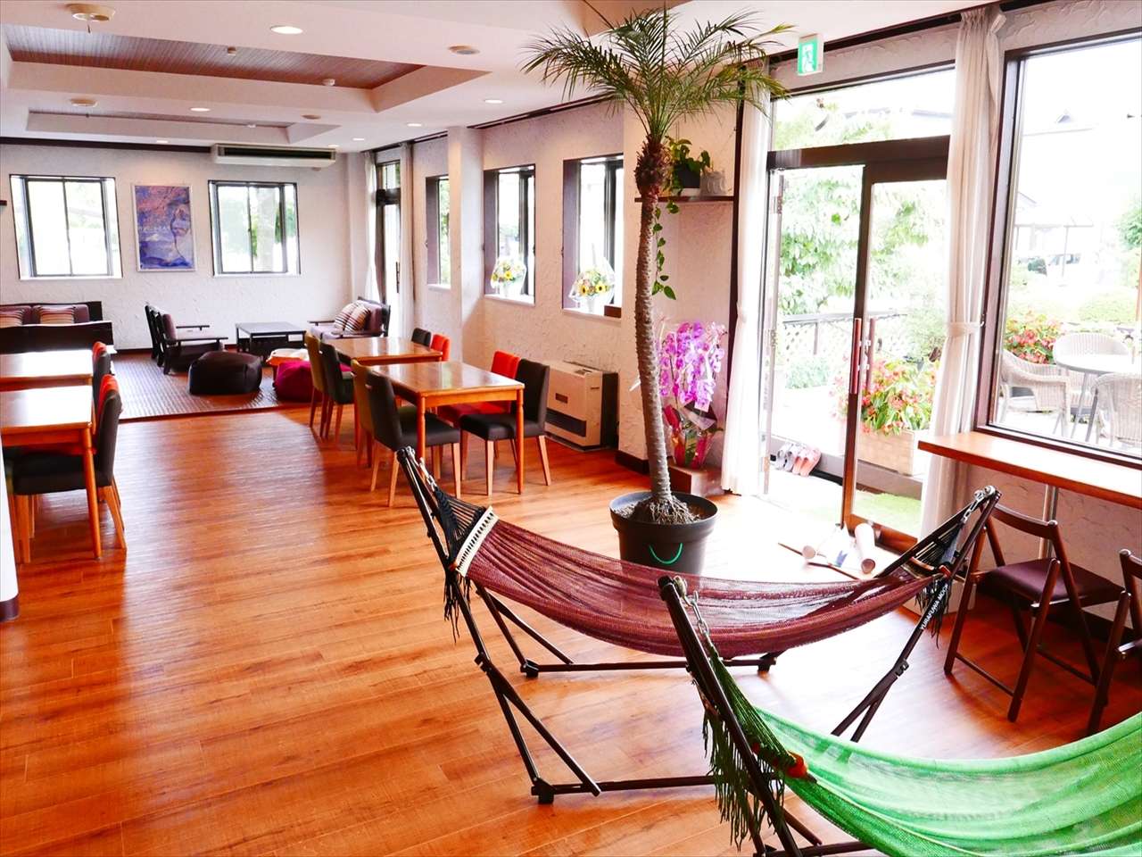 Bright shared common lounge and dining area with hammocks and garden-facing windows