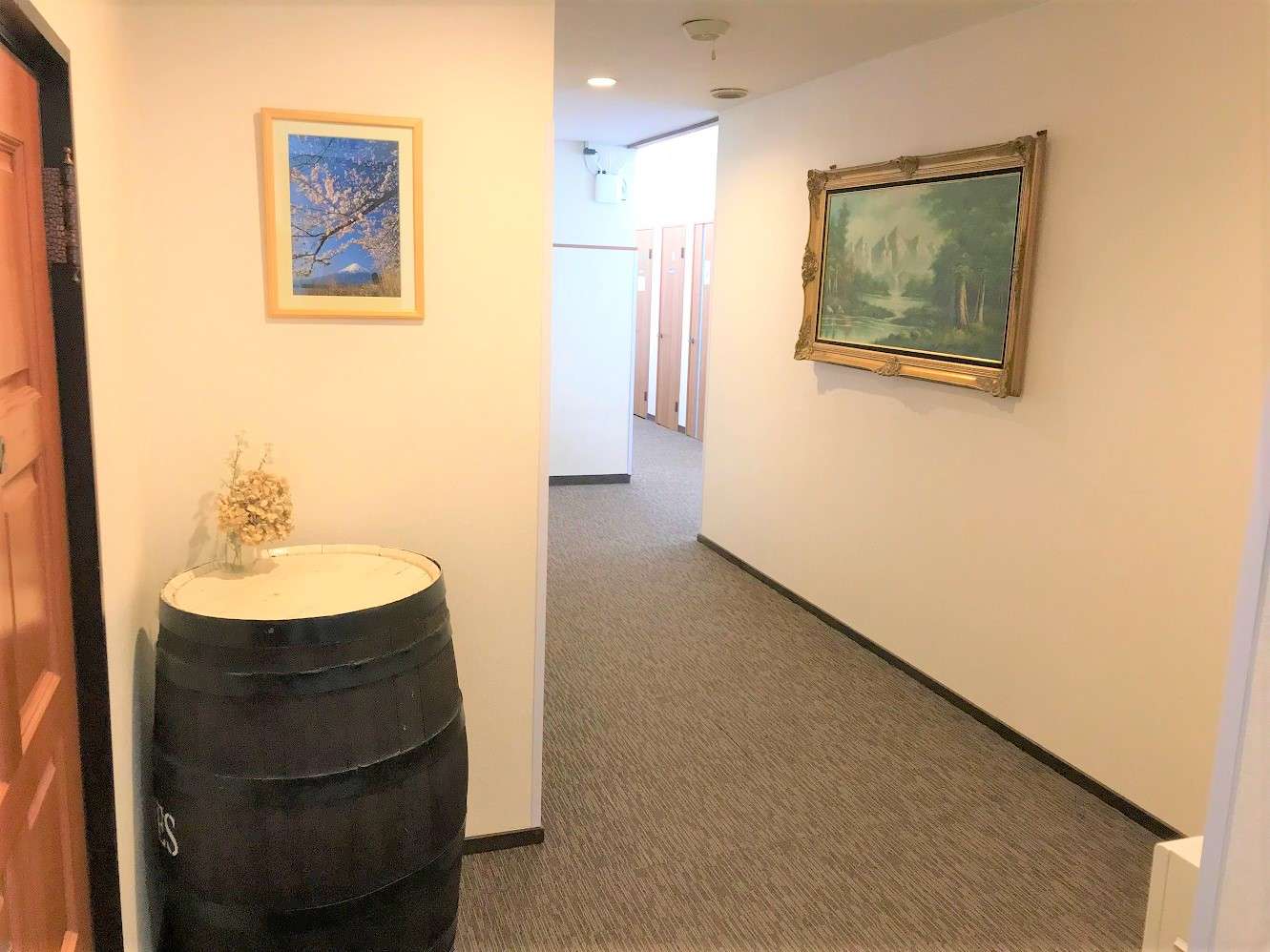 Carpeted interior hallway with framed Mount Fuji and landscape art and a wine-barrel accent