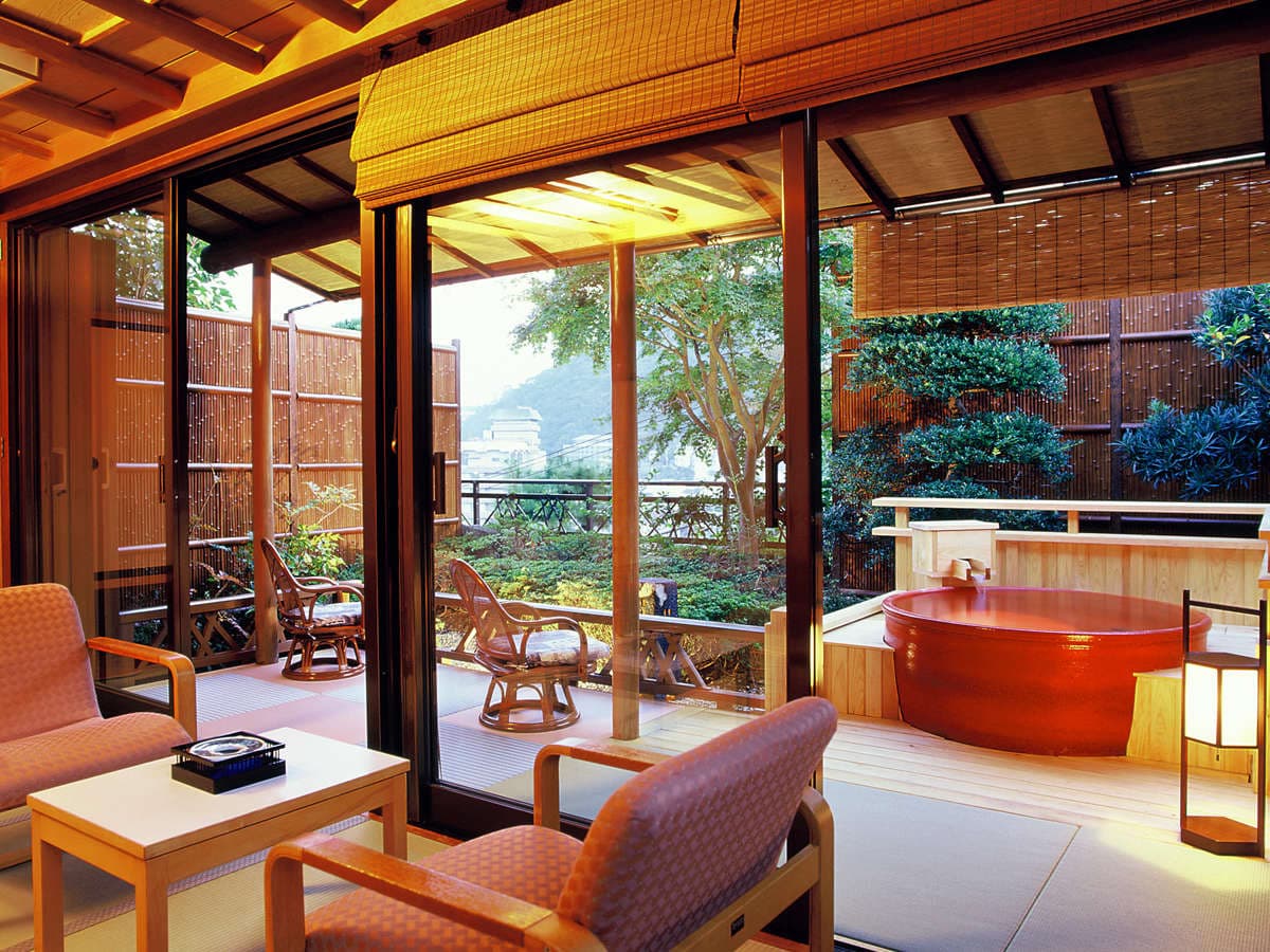Japanese guest room at Shin Kadoya with rattan chairs opening onto a private open-air cypress bath and garden