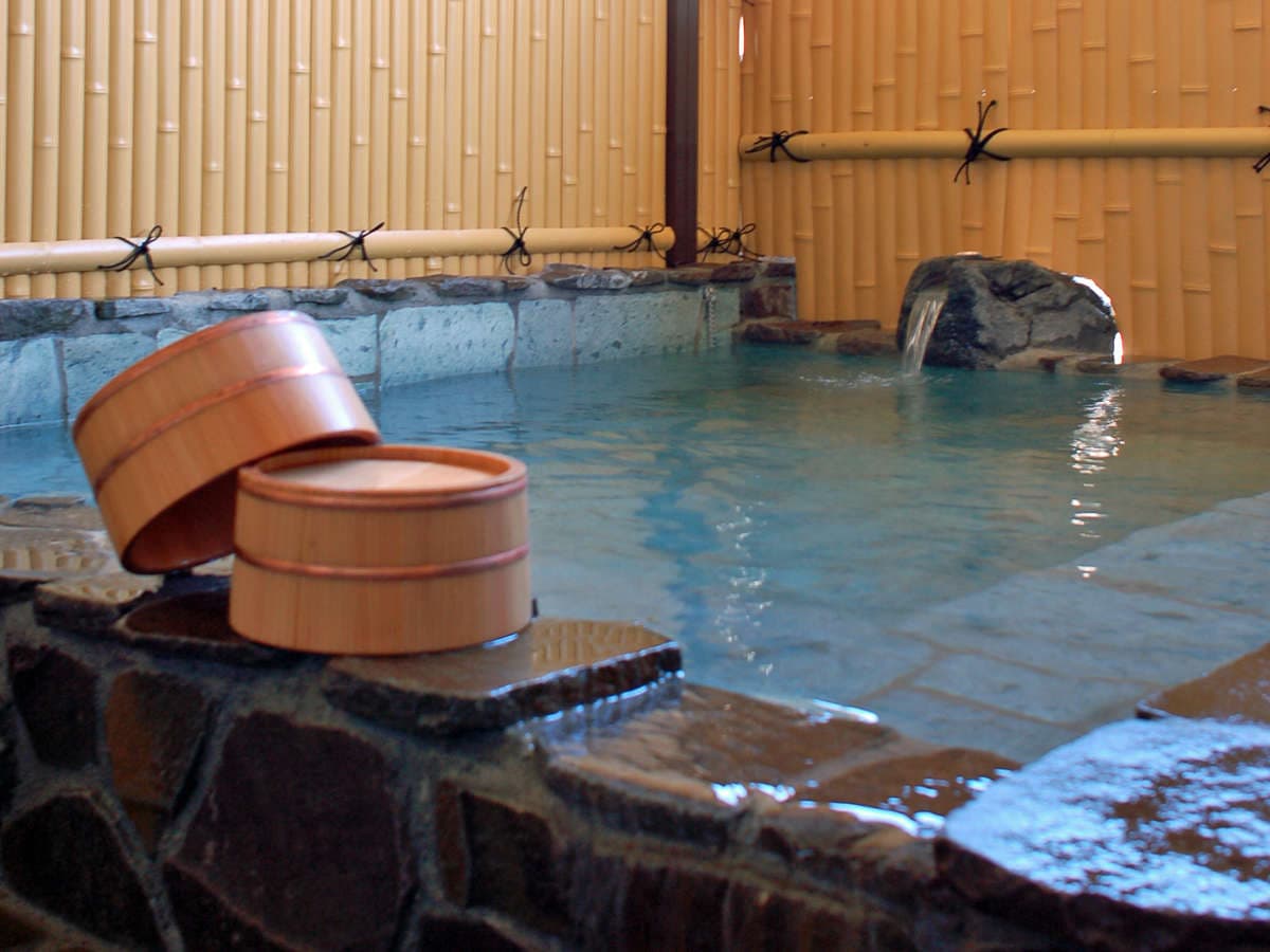 Open-air hot spring bath with wooden bath buckets and bamboo fencing at Shin Kadoya, Atami Onsen