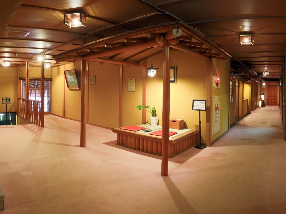 Spacious warm-toned lounge corridor with timber framing and tatami seating at Shin Kadoya, Atami Onsen