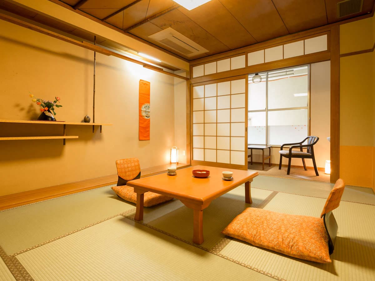 Traditional Japanese tatami room with floor cushions and hanging scroll at Dogo Grand Hotel