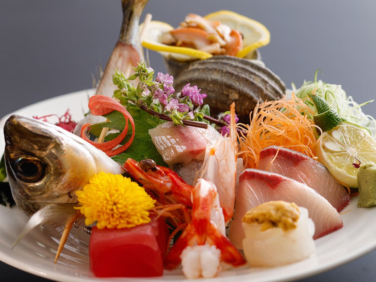 Fresh local sashimi platter with shrimp, sea bream and seasonal garnishes at Dogo Grand Hotel