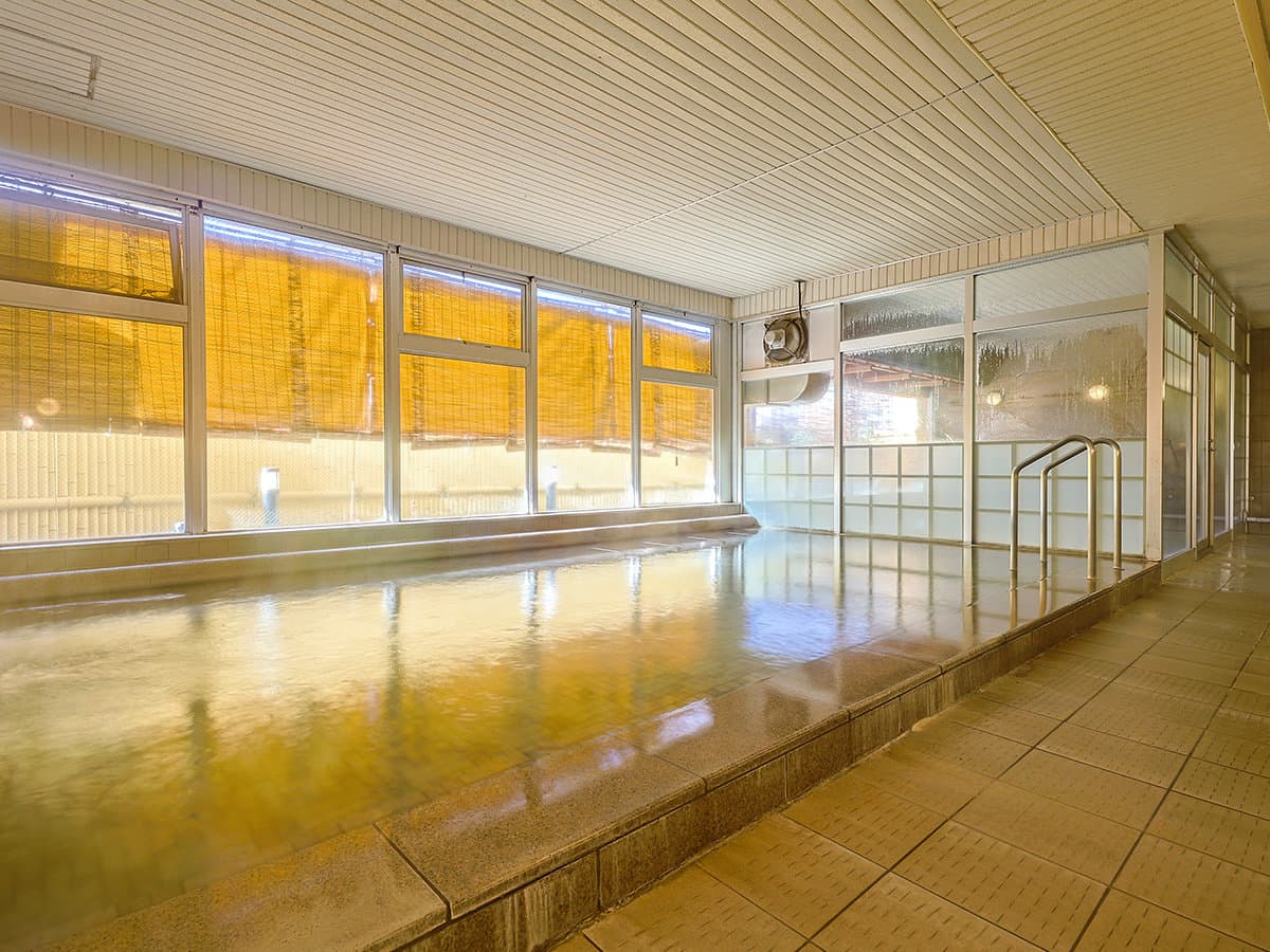 Bright indoor onsen bath with large windows in the Dogo Onsen thermal waters at Dogo Grand Hotel