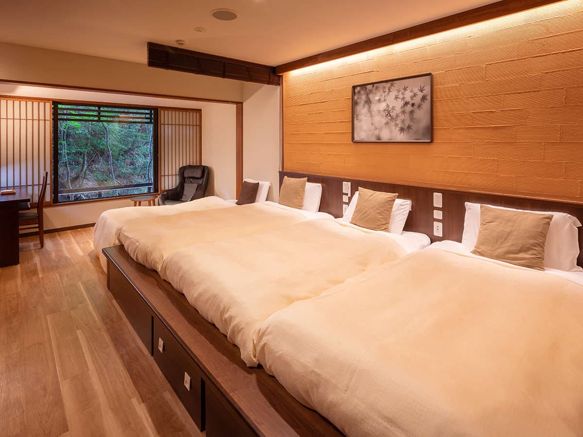 Spacious premium room with low wooden bed platform and forest-view window at Hotel Miyajima Villa