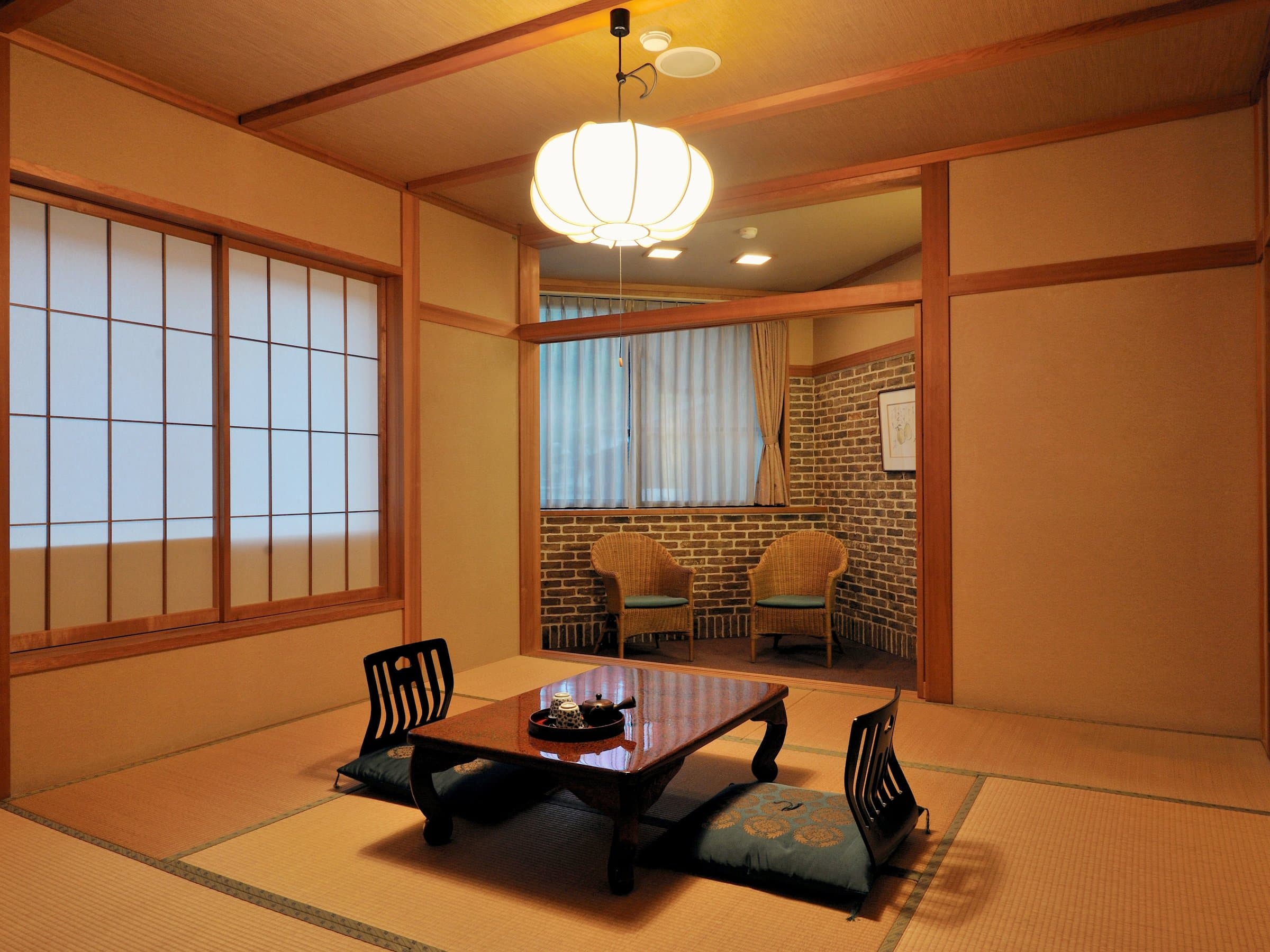 Bright Japanese-style tatami guest room with a lacquered low table, floor cushions and a round paper lantern at Shirouma-so