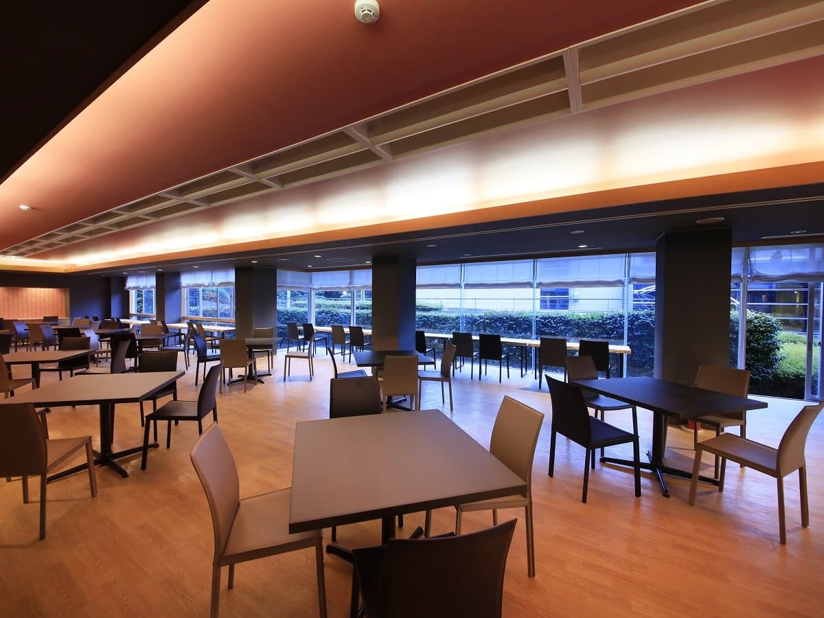 Bright dining hall at Atami Fuga with wooden tables and floor-to-ceiling windows facing the garden