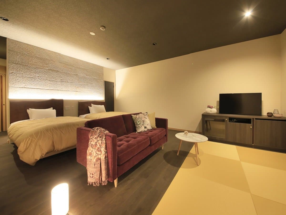 Modern Japanese-Western guest room at Atami Fuga with twin low beds, a velvet sofa and a tatami lounge area