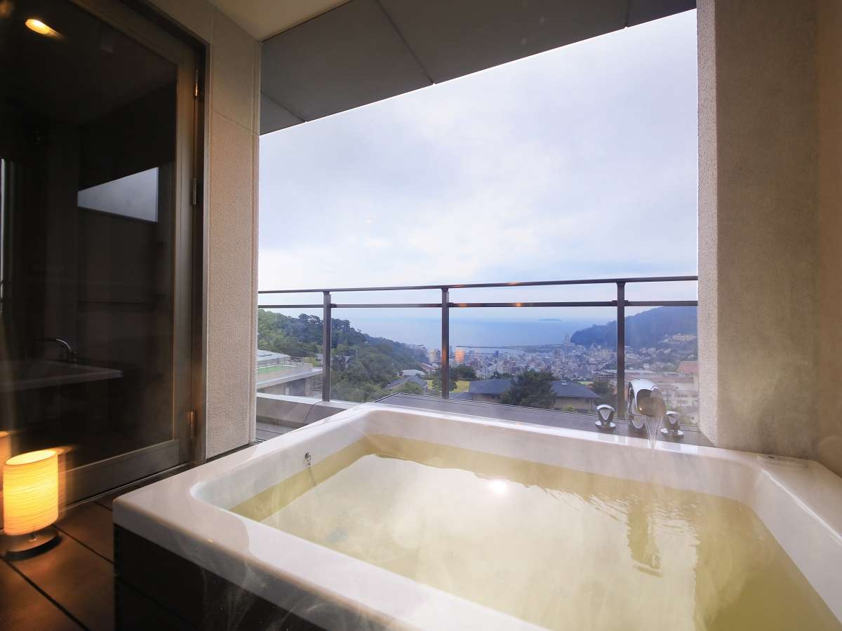 Private open-air bath on a guest-room balcony at Atami Fuga with a sweeping view over Atami town and the sea