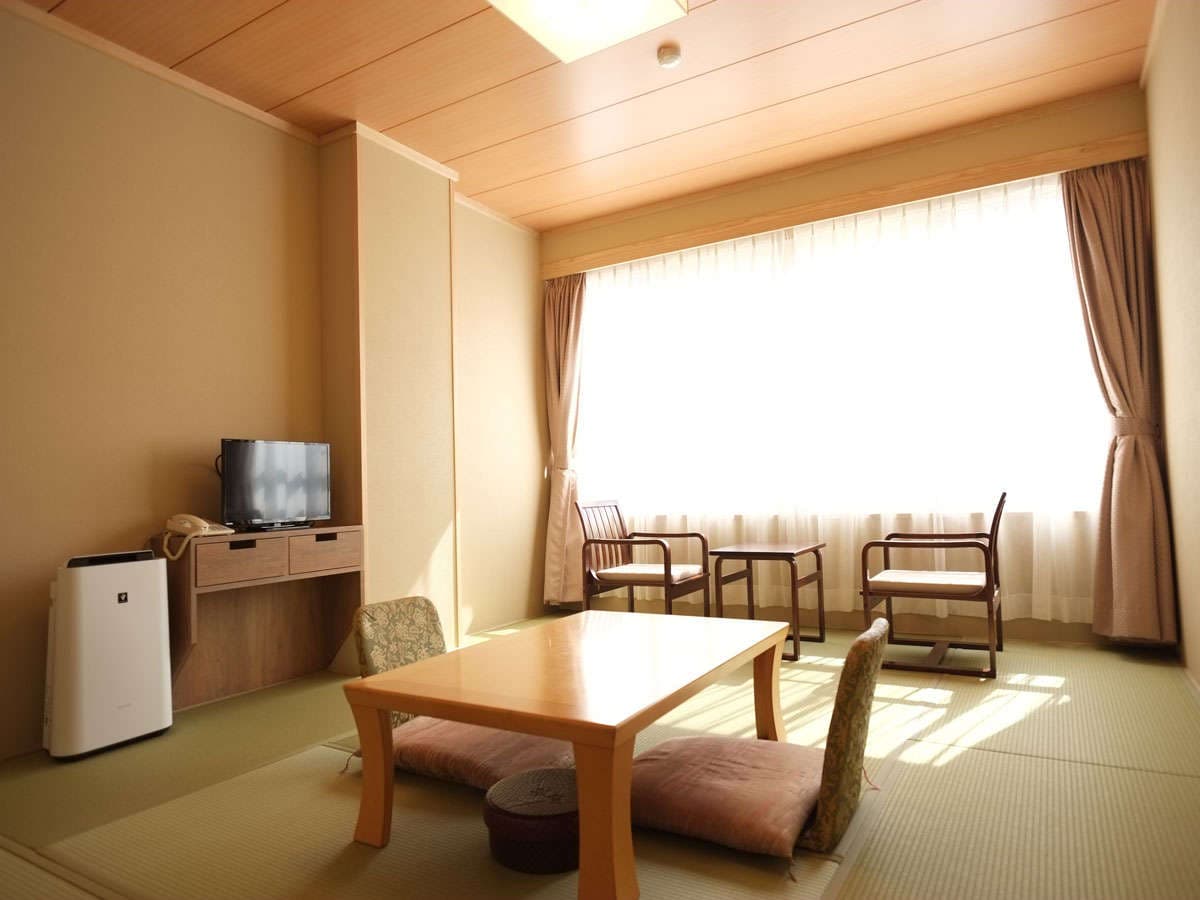 Japanese-style tatami guest room with low table, floor cushions and shoji screens at Hotel Harumoto in Nikko
