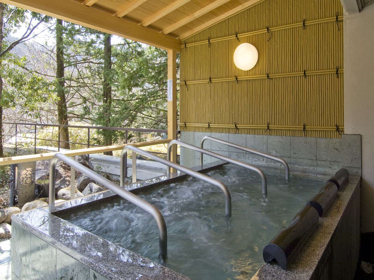 Open-air rotenburo bath with bamboo screen and forest view at Hotel Harumoto in Nikko