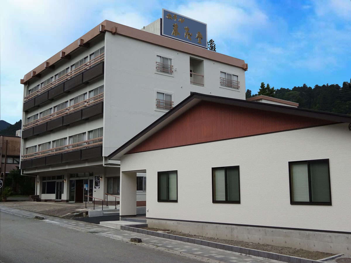 Daytime exterior of Hotel Harumoto, a mid-rise inn with traditional rooftop signage in central Nikko