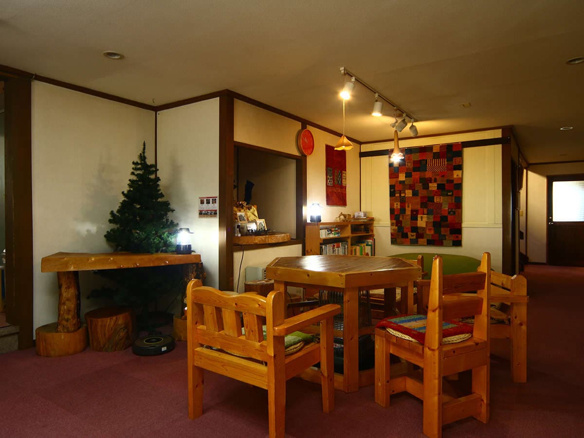 Cozy wood-furnished lounge area at Oomukou Ryokan with handmade timber chairs and a hexagonal table