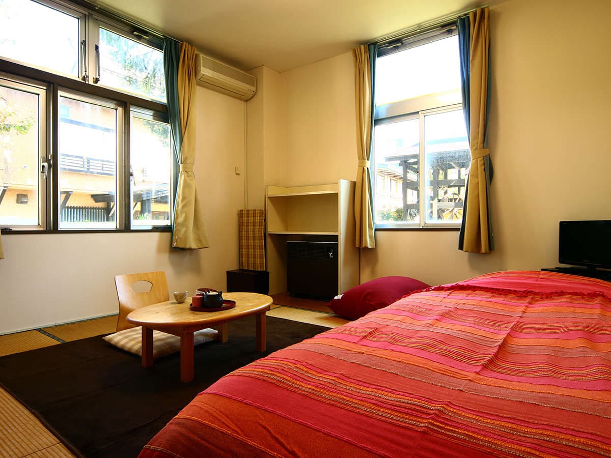 Bright guest room at Oomukou Ryokan with twin beds, large windows and mountain-side views in Happo Onsen