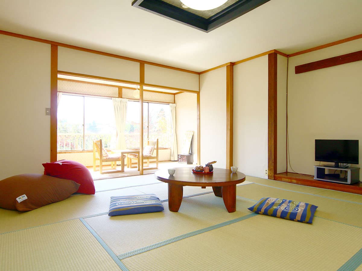 Spacious tatami guest room at Oomukou Ryokan with a low table and a balcony looking toward the Hakuba mountains