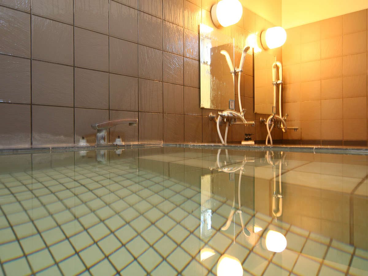 Atmospheric low-angle view of the green Happo Onsen water in the indoor bath at Oomukou Ryokan