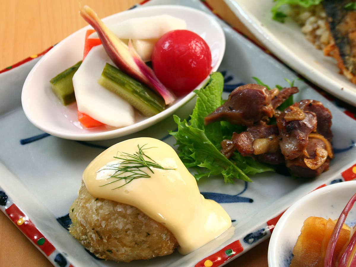 Home-style dinner appetizer plate at Oomukou Ryokan with a croquette, grilled meat and assorted pickled vegetables