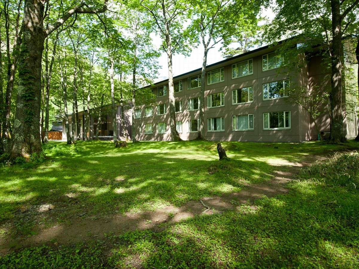 Kyukamura Nikko-Yumoto guesthouse exterior set among tall green trees near Yumoto Onsen in Nikko