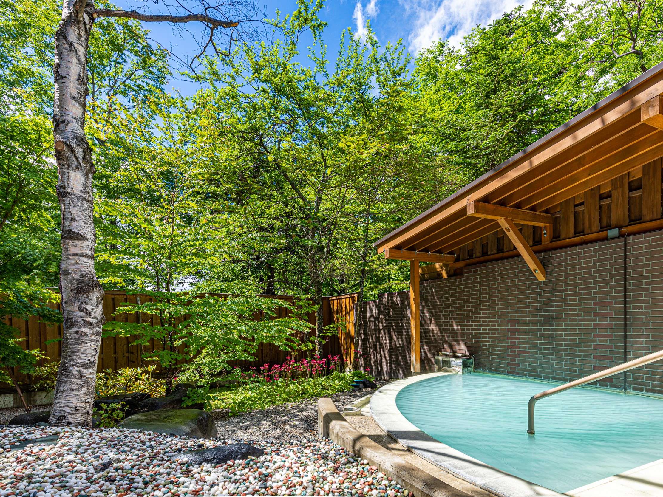 Open-air hot-spring bath surrounded by autumn foliage under a covered eave in Nikko Yumoto Onsen