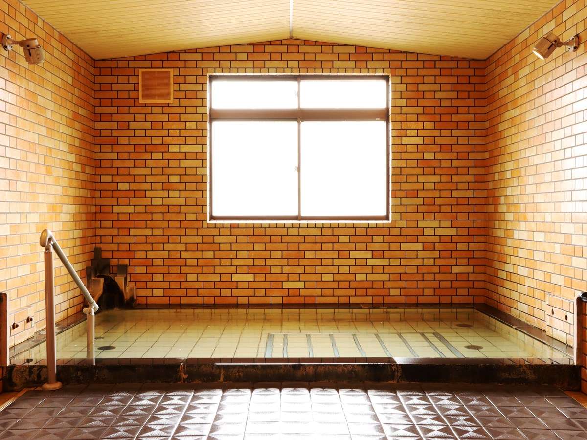 Second indoor onsen bath with warm brick walls and a quiet tiled tub at Hotel Cerulean Alpen, Hakuba
