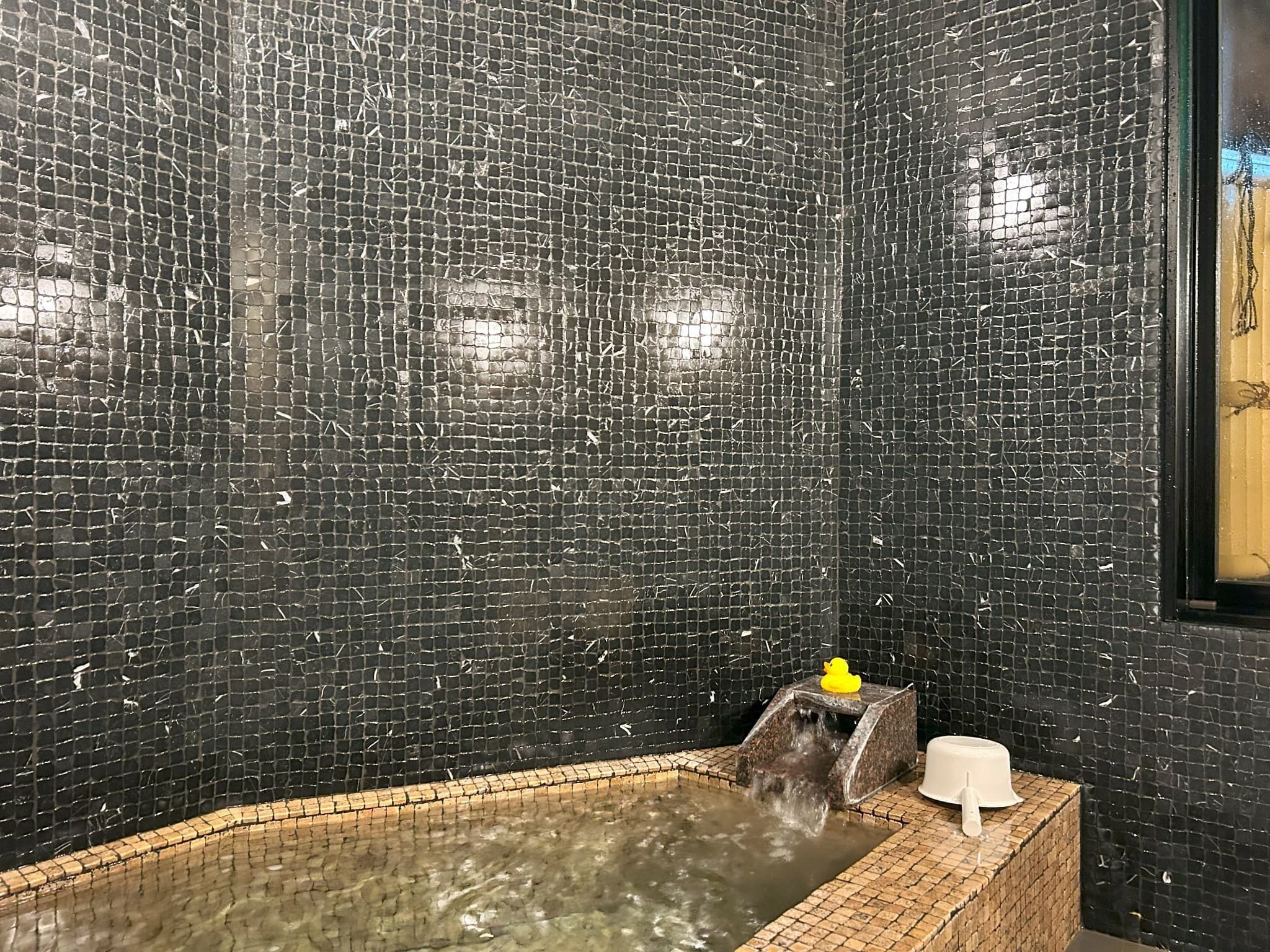 Yamatoya Ryokan Kinosaki Onsen indoor mosaic-tile onsen bath with bamboo water spout