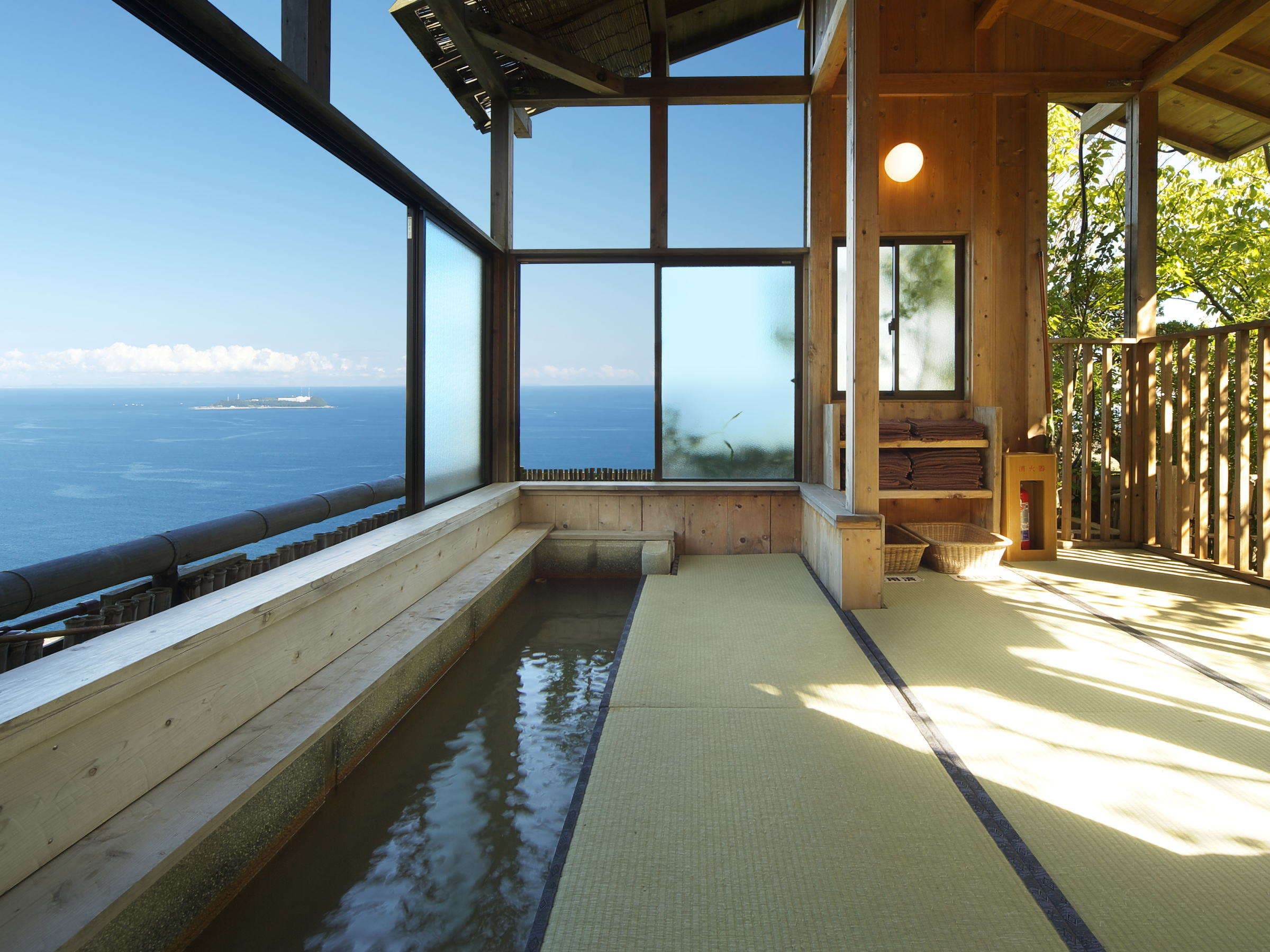 Glass-walled bathing terrace with tatami floor and footbath facing the Pacific Ocean at Chikurinan Mizuno