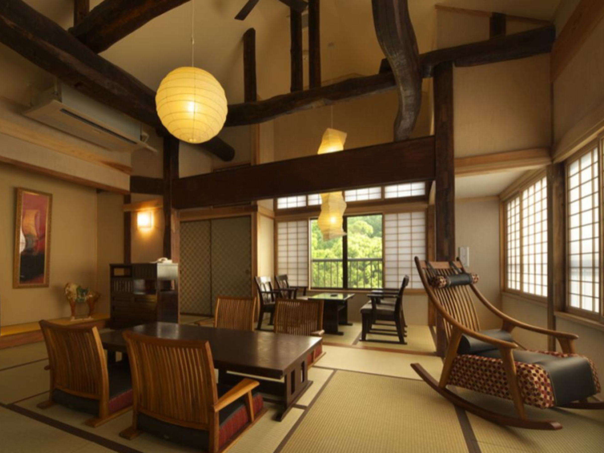 Spacious tatami guest room with low table, rocking chairs and high timber-beamed ceiling at Chikurinan Mizuno