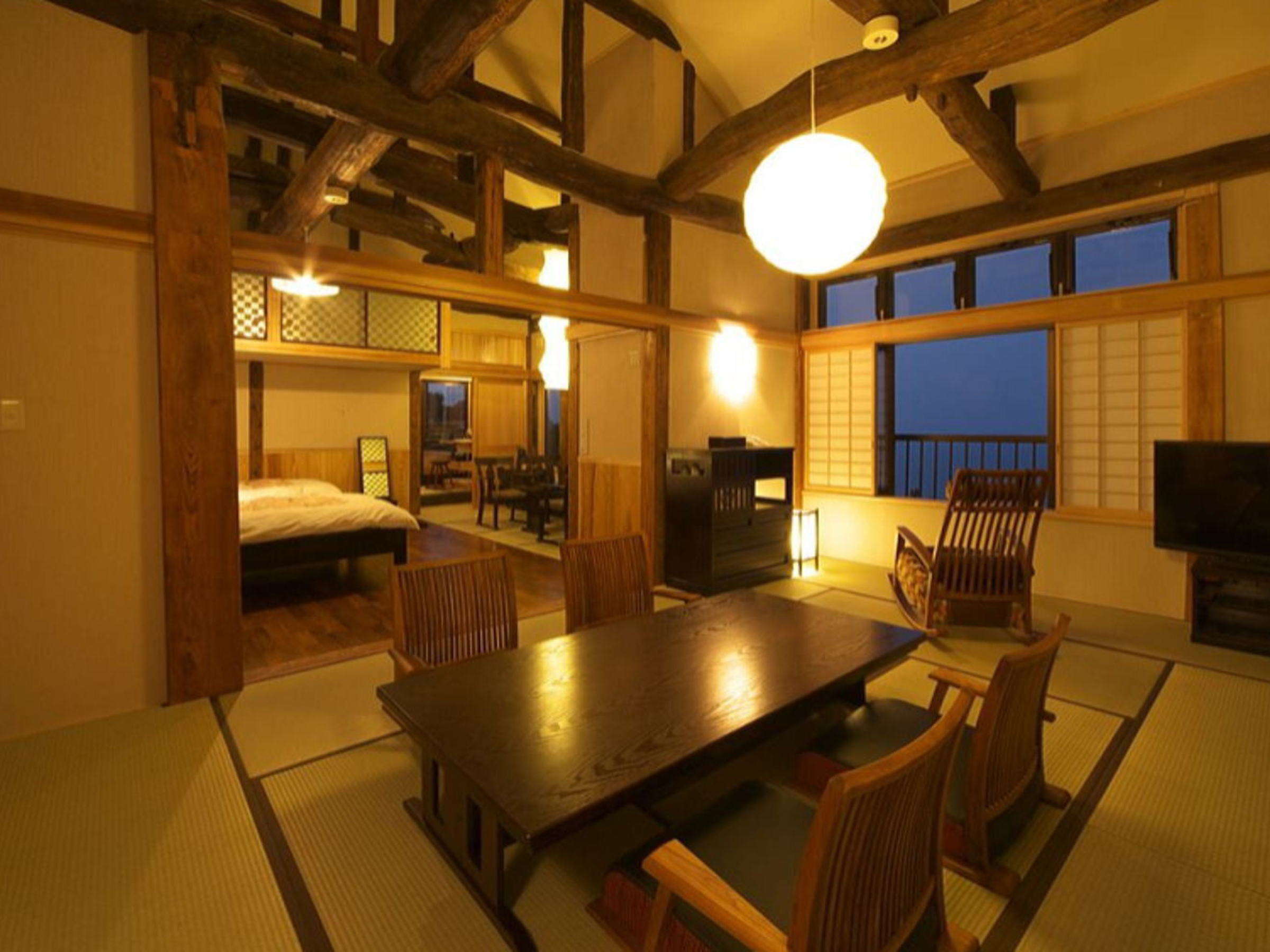 Premium tatami guest room with exposed beams, paper lantern and ocean view at dusk at Chikurinan Mizuno