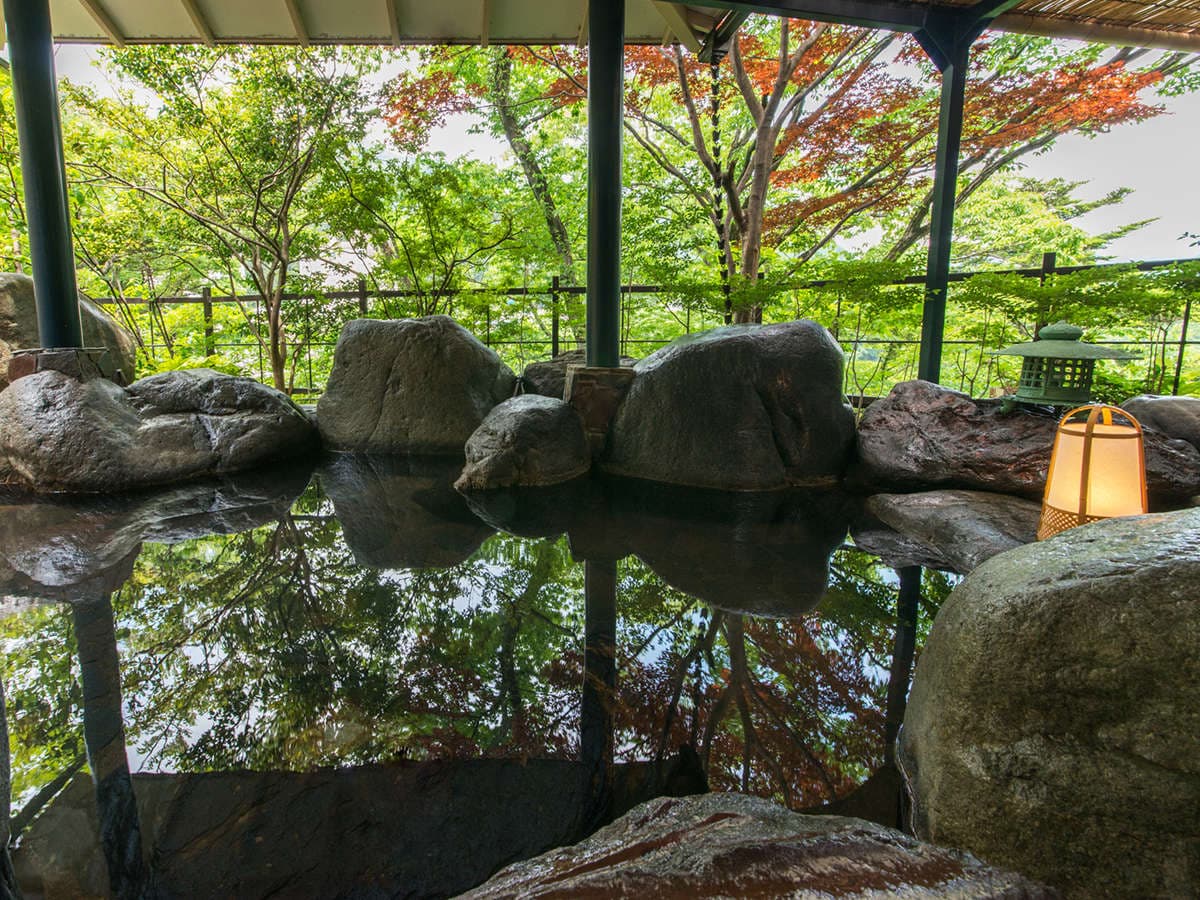 Open-air rotenburo bath ringed by boulders and a stone lantern amid maple foliage at Kinugawa Park Hotels