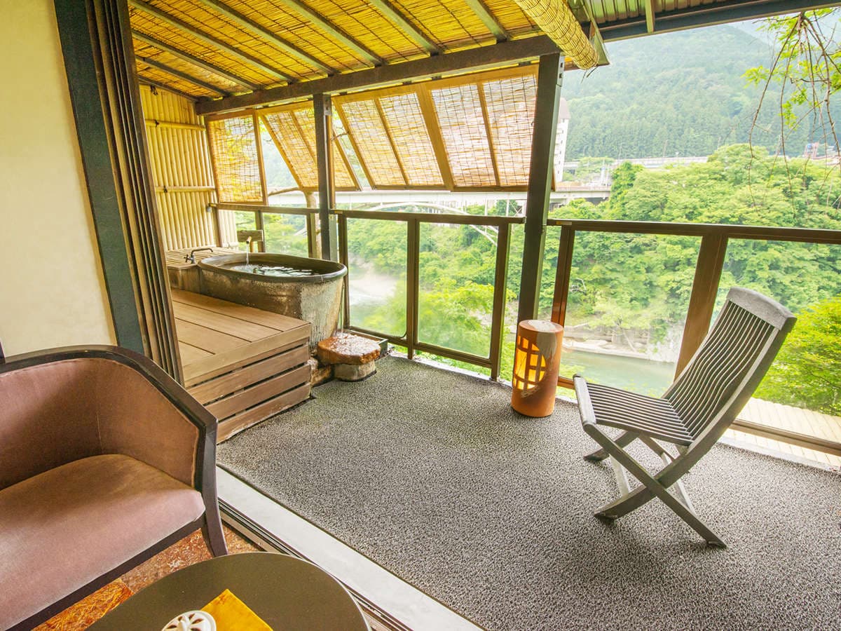 Guest room terrace with private stone open-air bath overlooking the Kinugawa River valley
