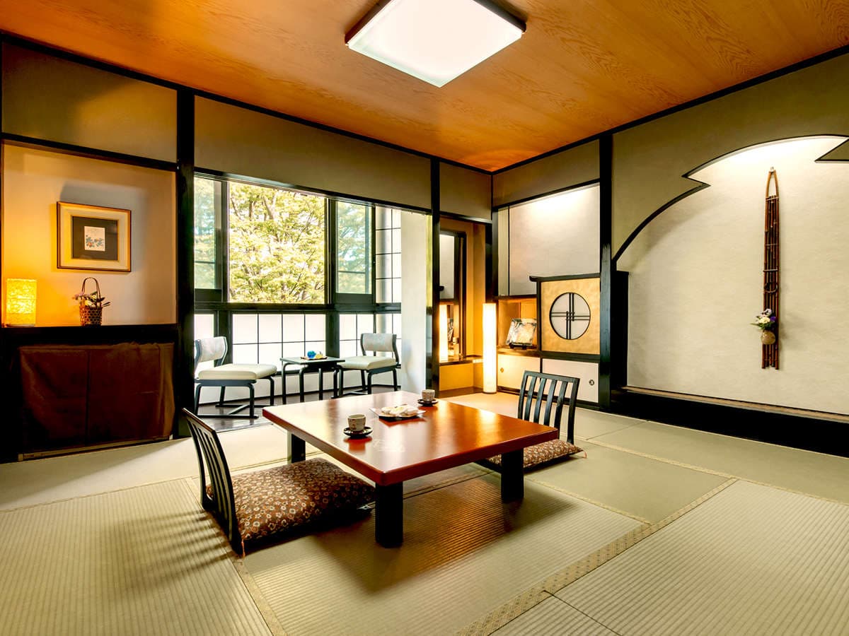 Spacious tatami guest room with low table and floor cushions and forest view at Kinugawa Park Hotels