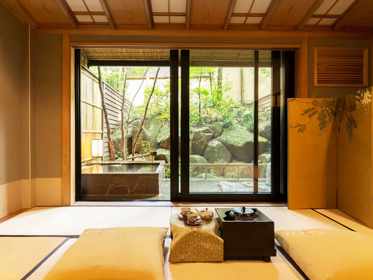 Tatami guest room opening onto a private stone soaking tub and rock garden at Kinugawa Park Hotels