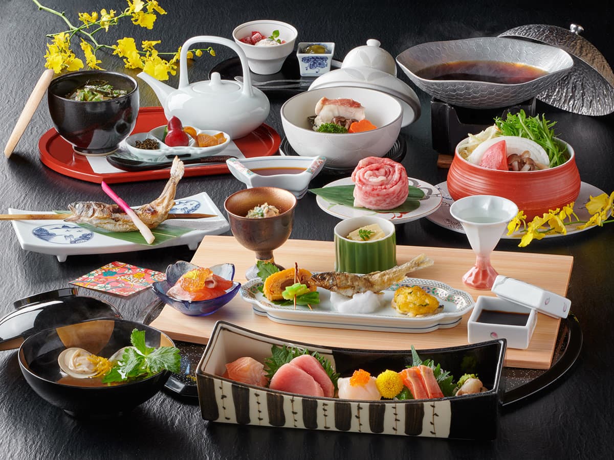 Seasonal kaiseki dinner spread of sashimi, grilled fish and small plates on black lacquerware at Kinugawa Park Hotels
