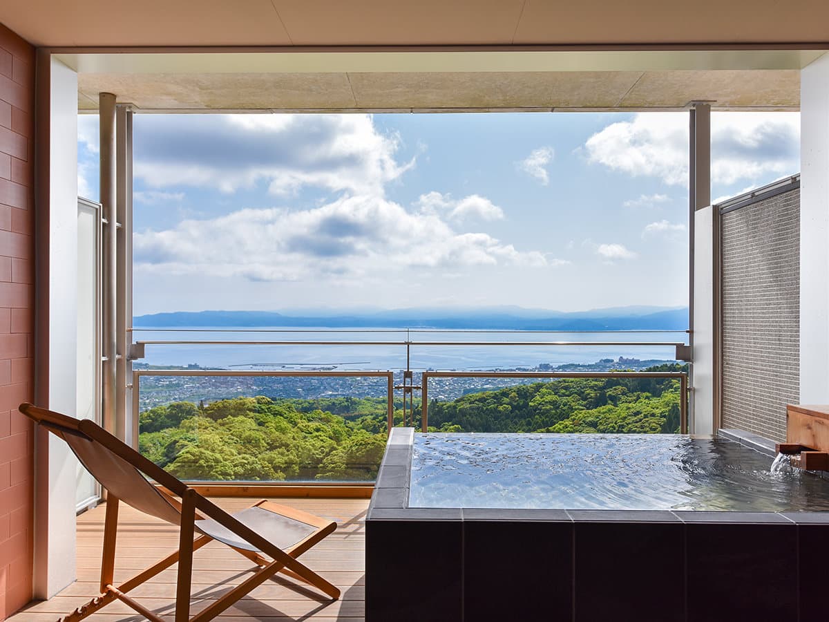 Private open-air bath on a guest-room terrace overlooking forest and Kagoshima Bay at Bettei Amafuru Oka, Ibusuki