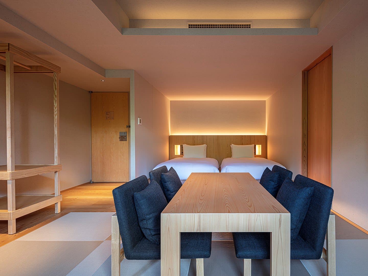 Warmly lit twin guest room at SOKI ATAMI with a long dining table and tatami flooring