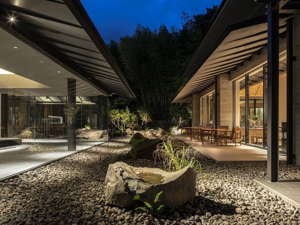 Illuminated courtyard garden with stone basin and gravel between the pavilions of SOKI ATAMI at dusk