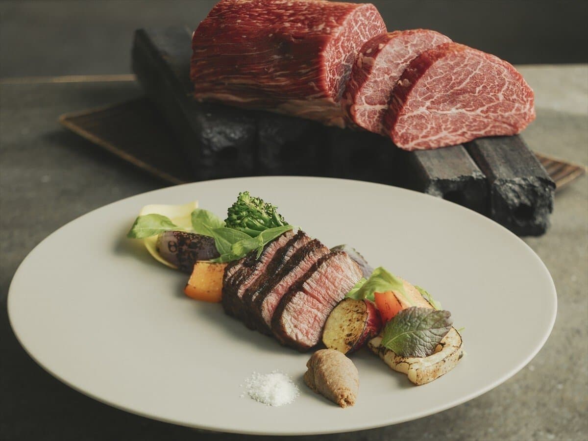 Grilled wagyu beef course at SOKI ATAMI plated with seasonal vegetables and raw marbled cuts behind