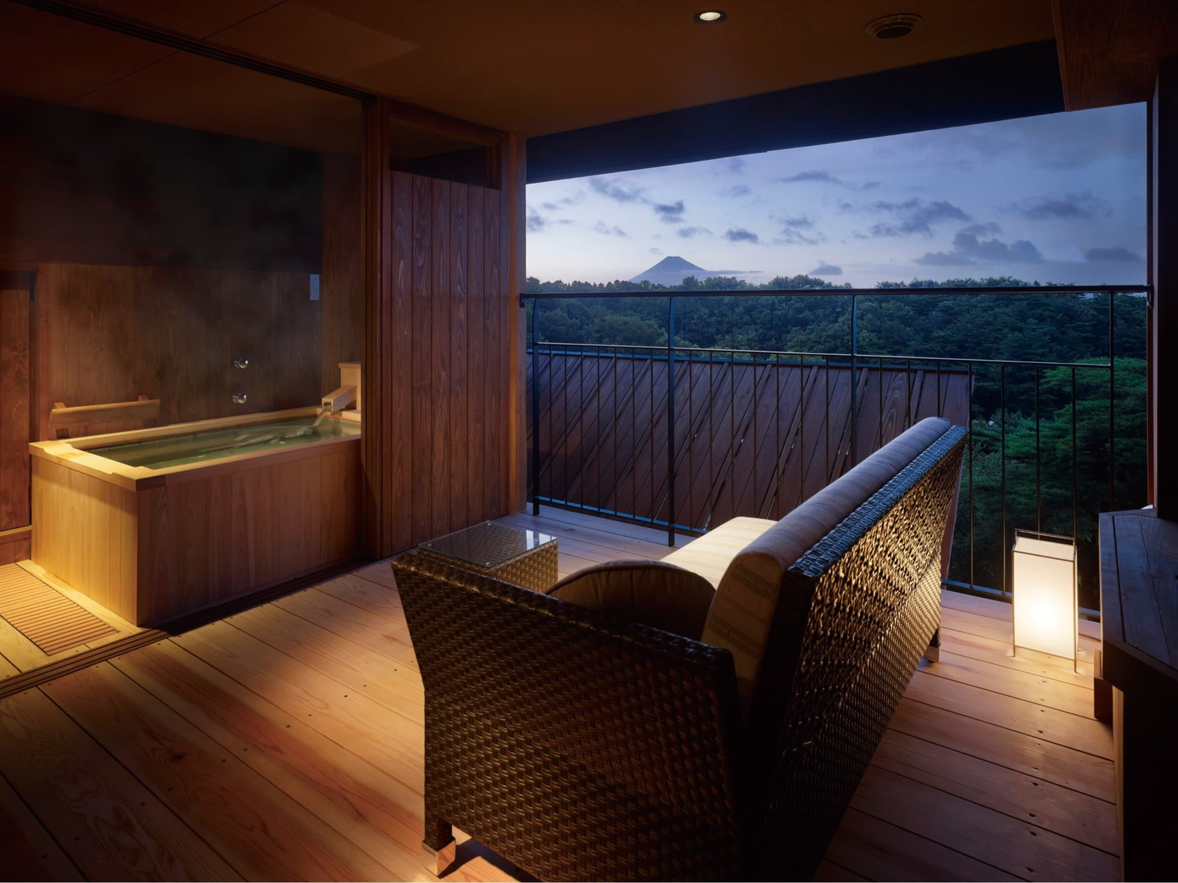 Private cypress in-room bath and terrace at dusk with a distant Mt. Fuji view at Sanshi Suimei in Shuzenji Onsen