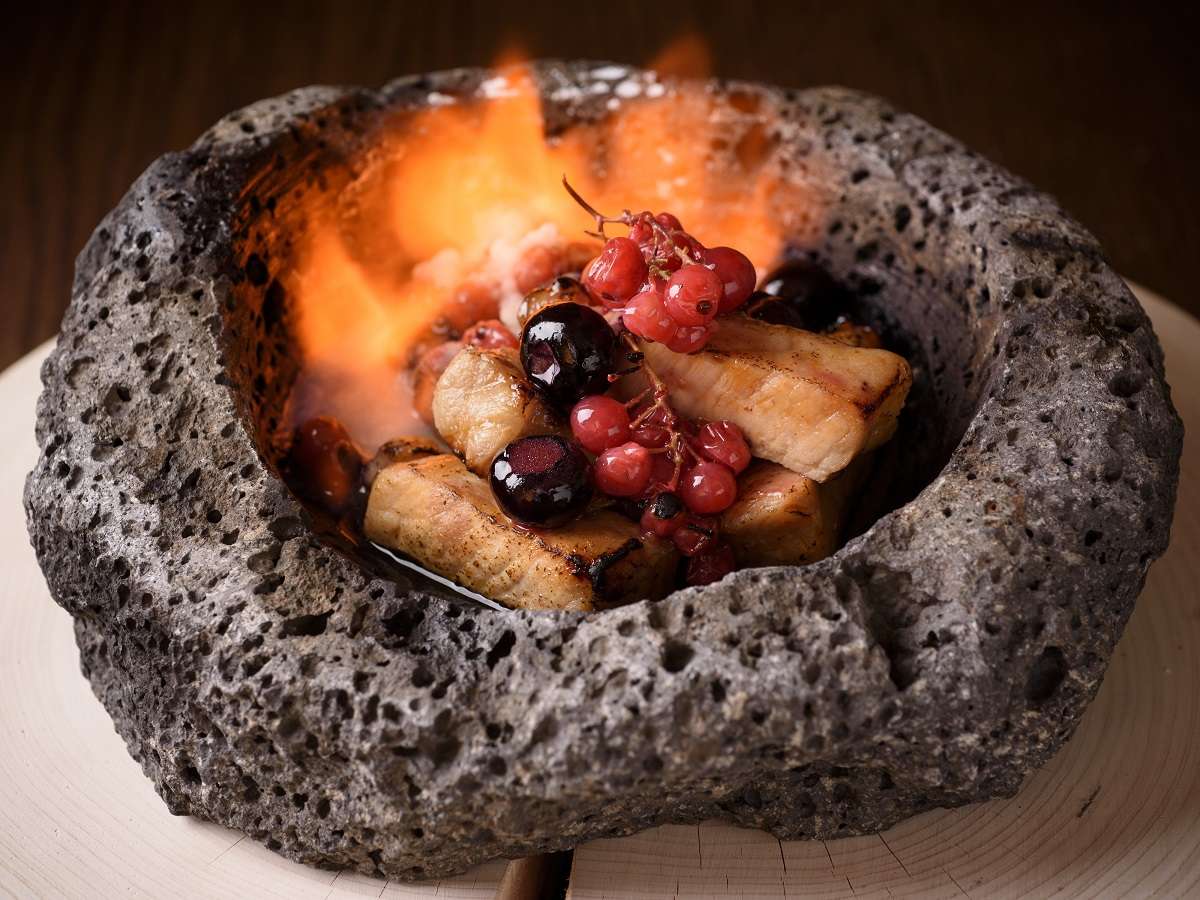 Flame-grilled meat with cherries and red currants served in a hollowed lava stone at Fufu Kawaguchiko