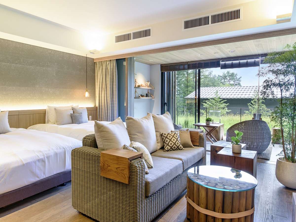 Twin-bed guest room at Fufu Kawaguchiko with a woven sofa lounge and garden-view glass wall