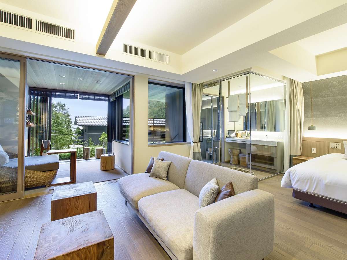 Spacious Fufu Kawaguchiko premium suite with a living lounge, bed and open vanity opening onto a forest terrace