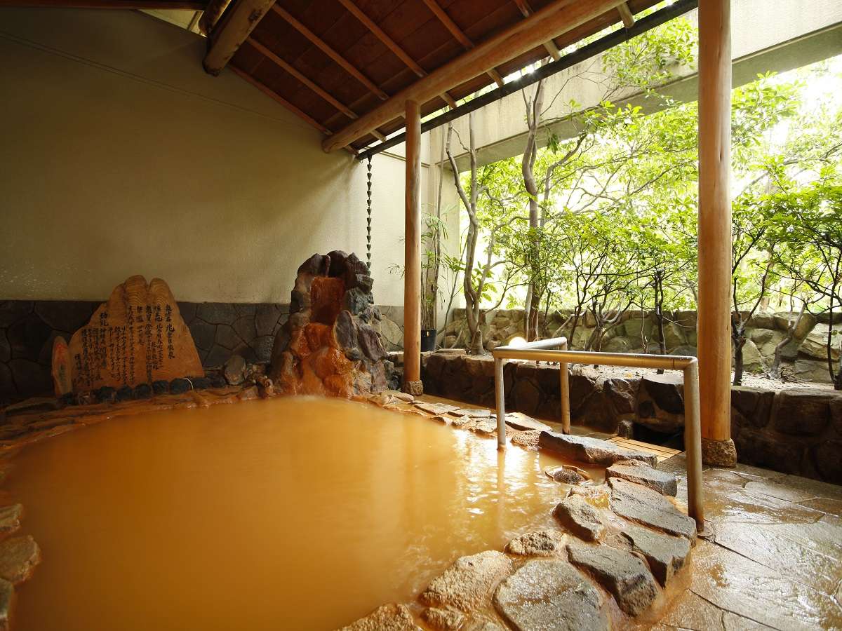Outdoor stone rotenburo with golden kinsen iron-spring water and a carved stone tablet at Spa Terrace Shisui