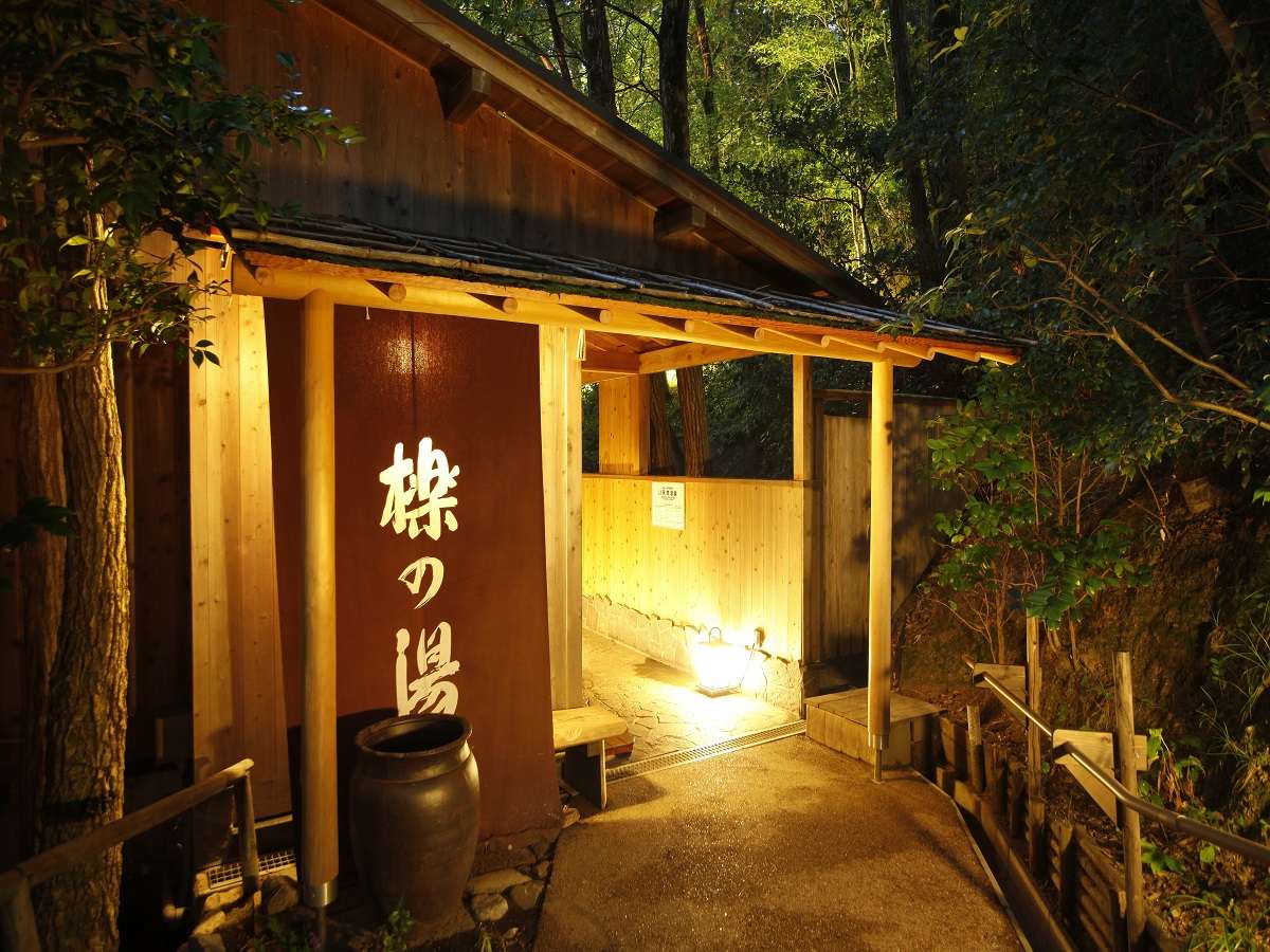 Illuminated wooden Hotaru-no-Yu bathhouse entrance with hanging noren at night, Spa Terrace Shisui
