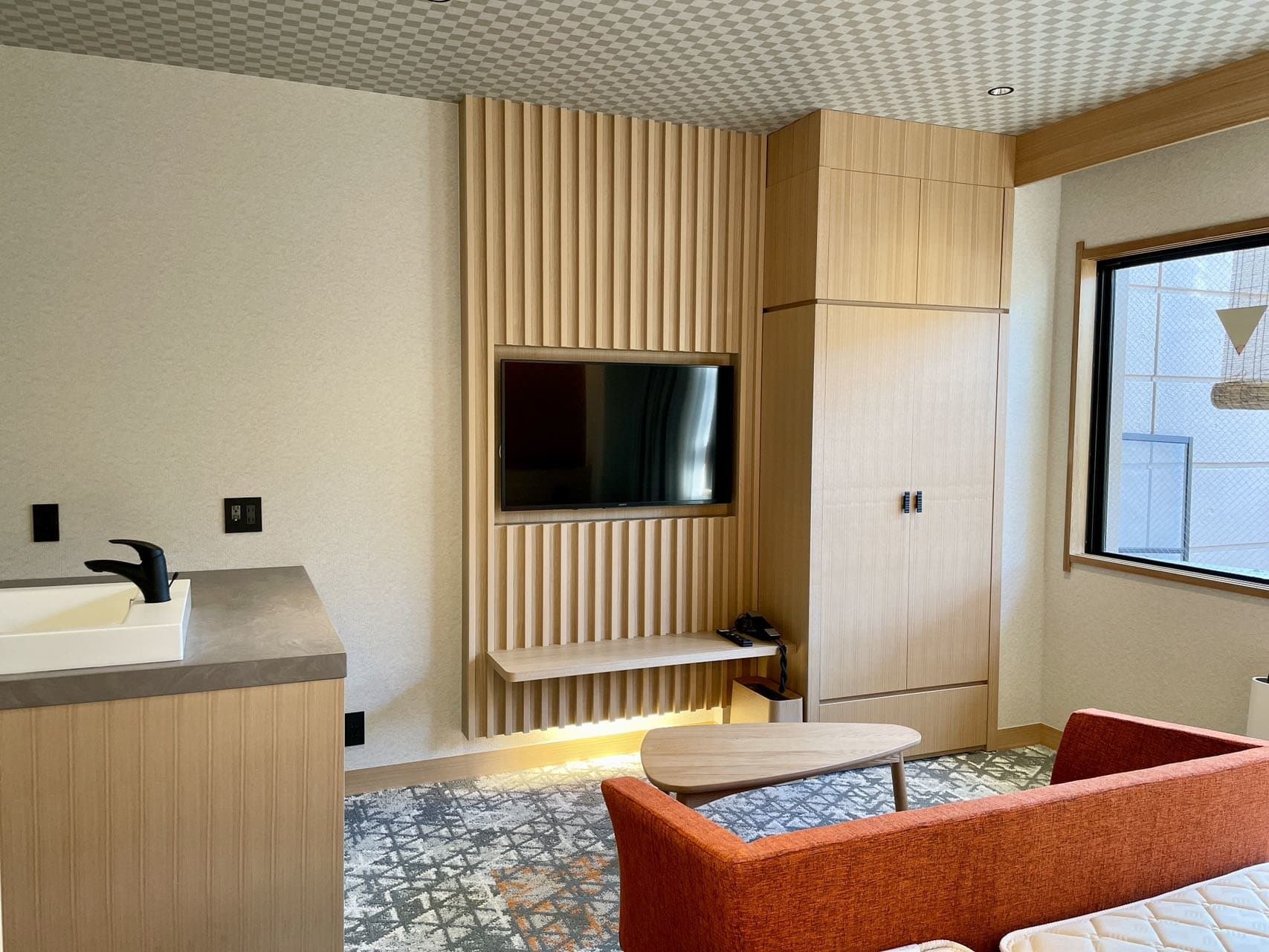 Modern guest room with lounge sofa, wood-slat wall and garden window at Spa Terrace Shisui